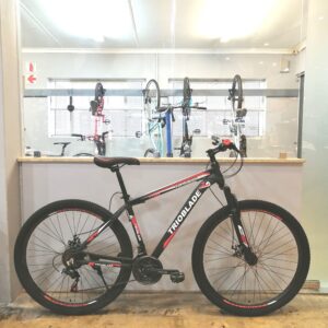 Trioblade 29" mountain bike with a medium alloy frame in Shimano Red, featuring a Shimano 21-speed drivetrain, front suspension fork, and cable disc brakes.